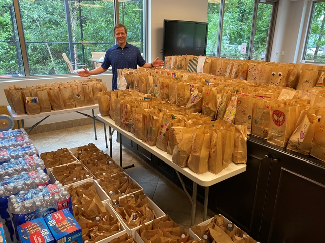 Kurt Arnold standing next to 600 lunches for Kids' Meals Inc.